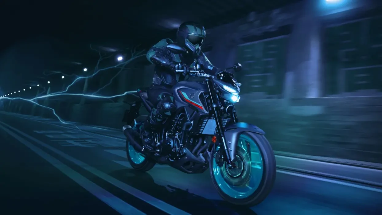Action image of Yamaha MT-03 LAMS roadster in grey/aqua colourway, front three quarter right tracking, travelling through cityscape at night