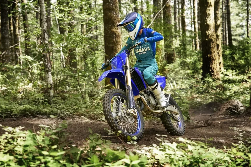 Action image of Yamaha YZ125X two stroke in blue colourway, riding through forest track