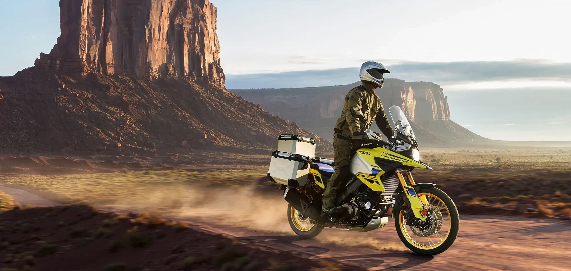 Action image of Suzuki V-Strom 1050DE adventure motorcycle in Champion Yellow, travelling through desert plain landscape