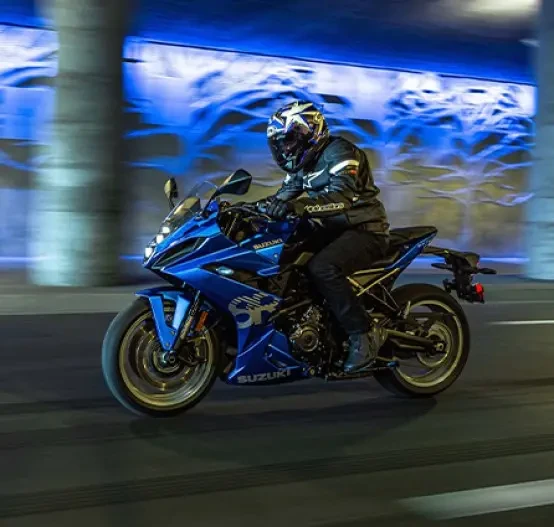 Action image of Suzuki GSX-8R in Blue colourway, riding through city at night with neon signs