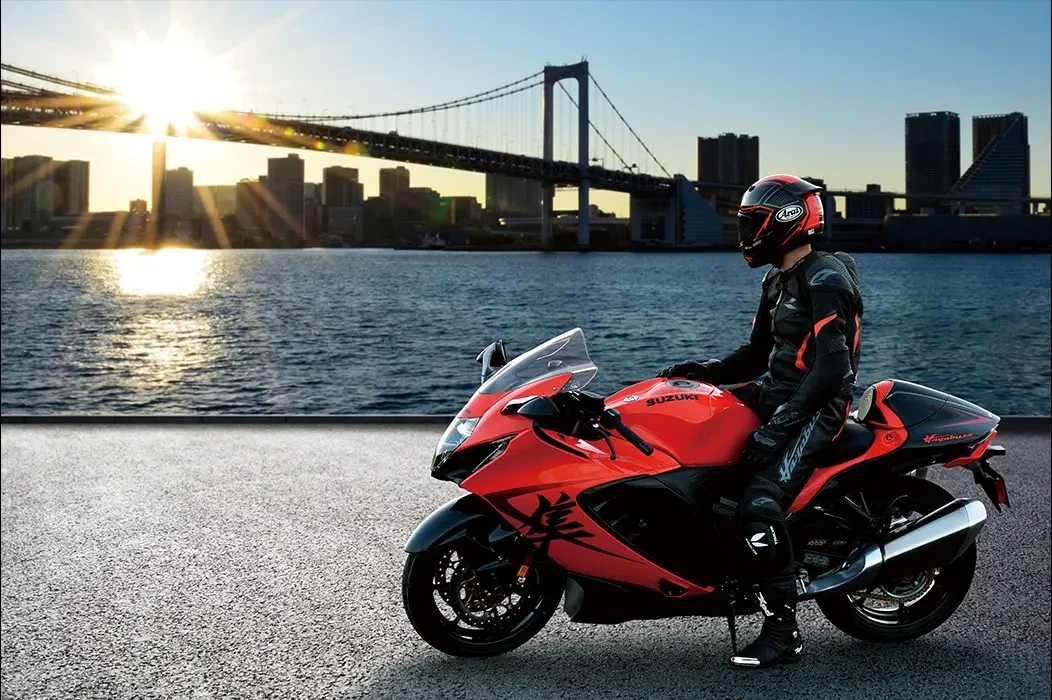 Rider sitting on Suzuki Hayabusa 25th anniversary at sunset with bridge in background