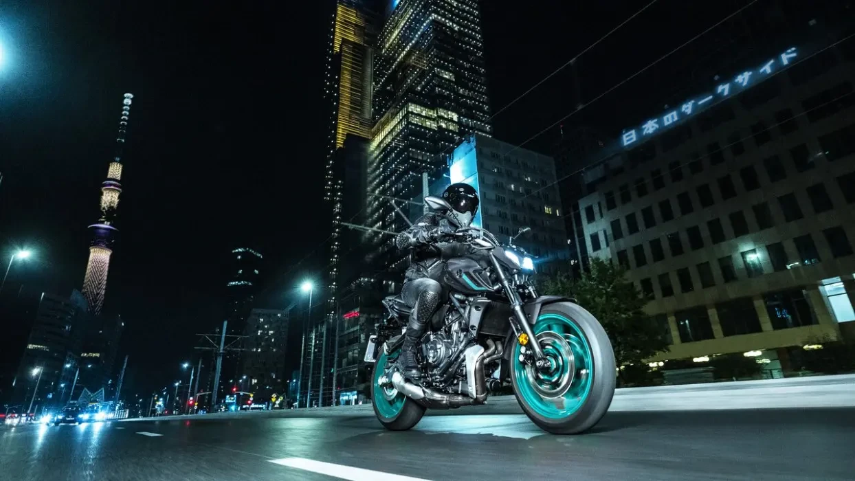 Action image of Yamaha MT-07 2024 in Grey Colourway, front three quarter tracking shot at night in a neon-coloured cityscape
