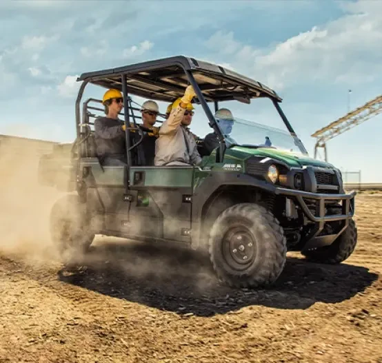 Outdoor action image of Kawasaki Mule DXT (Diesel), vehicle driving crew of workers around a job site