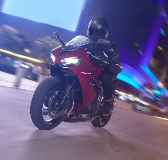Action image of Triumph Daytona 660 2024 in Carnival Red colourway, riding through city at night