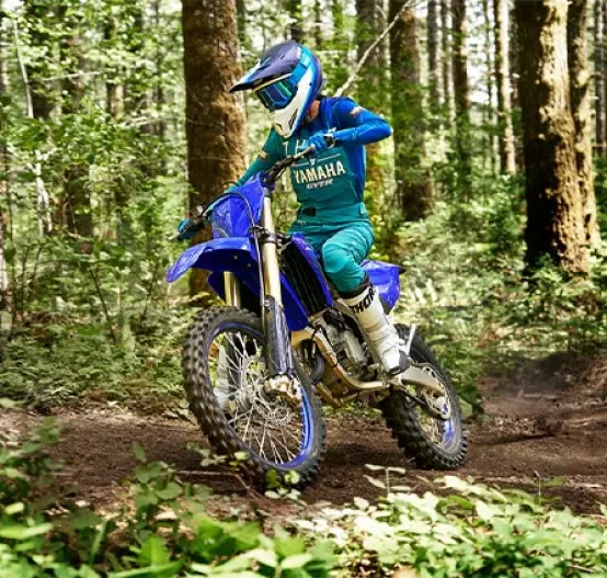 Action image of Yamaha YZ125X two stroke in blue colourway, riding through forest track