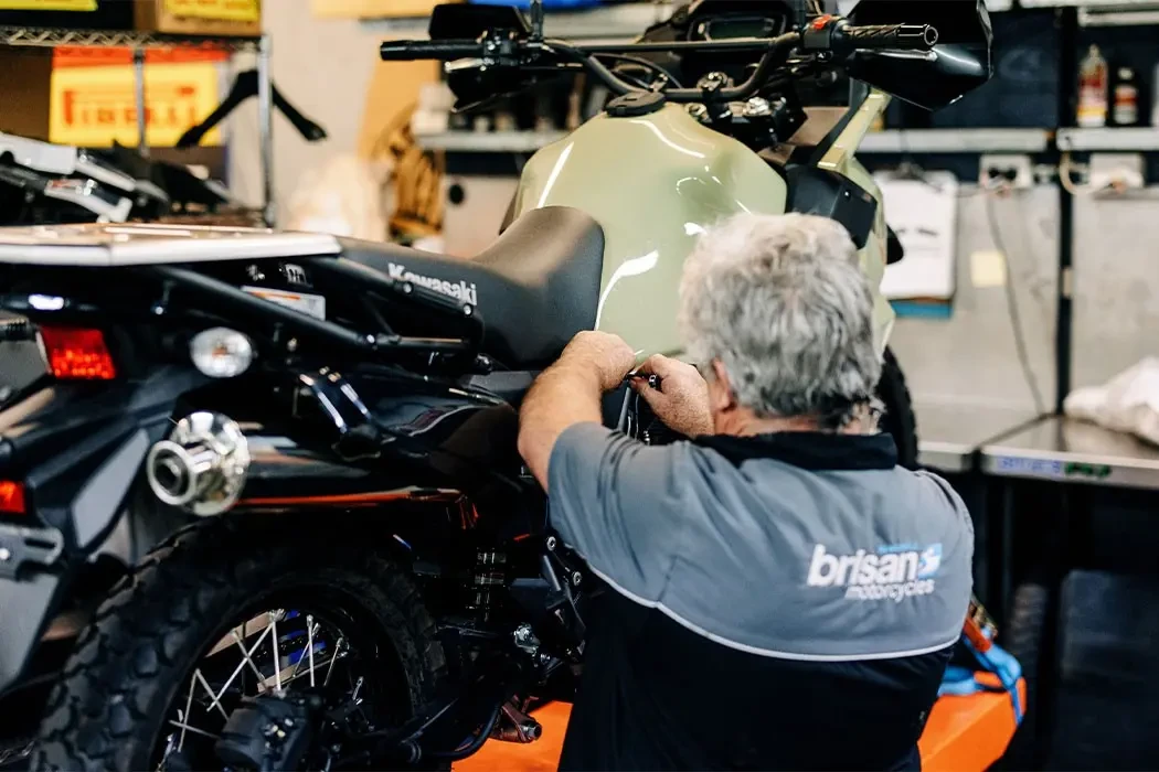 Motorcycle technician servicing a Kawasaki KLR650 at Brisan Motorcycles Newcastle