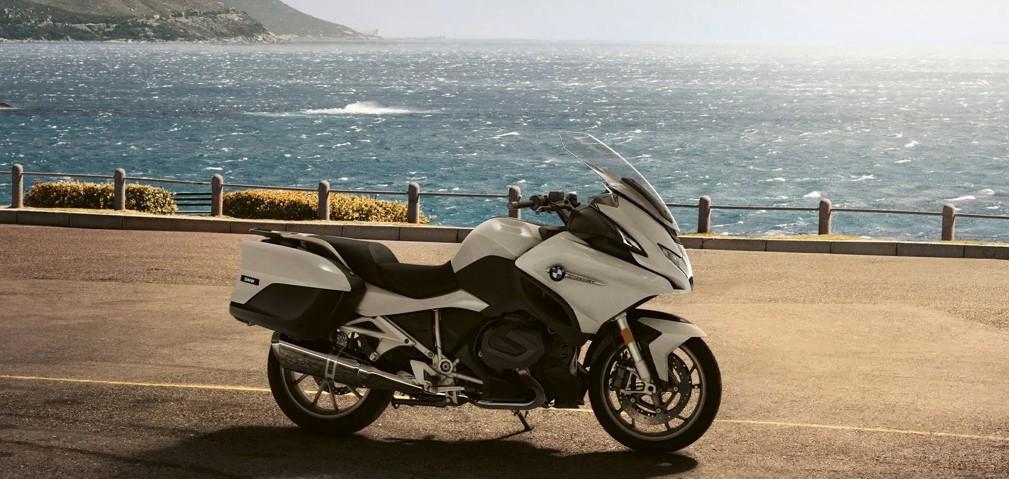Static image of BMW R 1250 RT touring motorcycle, parked on a mountain road by the sea