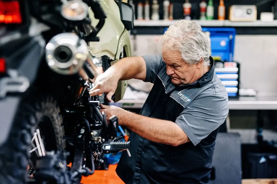 Motorcycle technician servicing a Kawasaki KLR650 at Brisan Motorcycles Newcastle